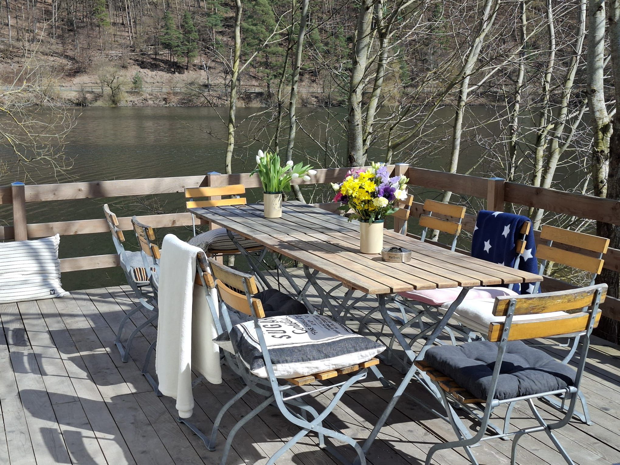 Gedeckte Holzterrasse mit Frühlingsblumen und direktem Blick auf den Edersee
